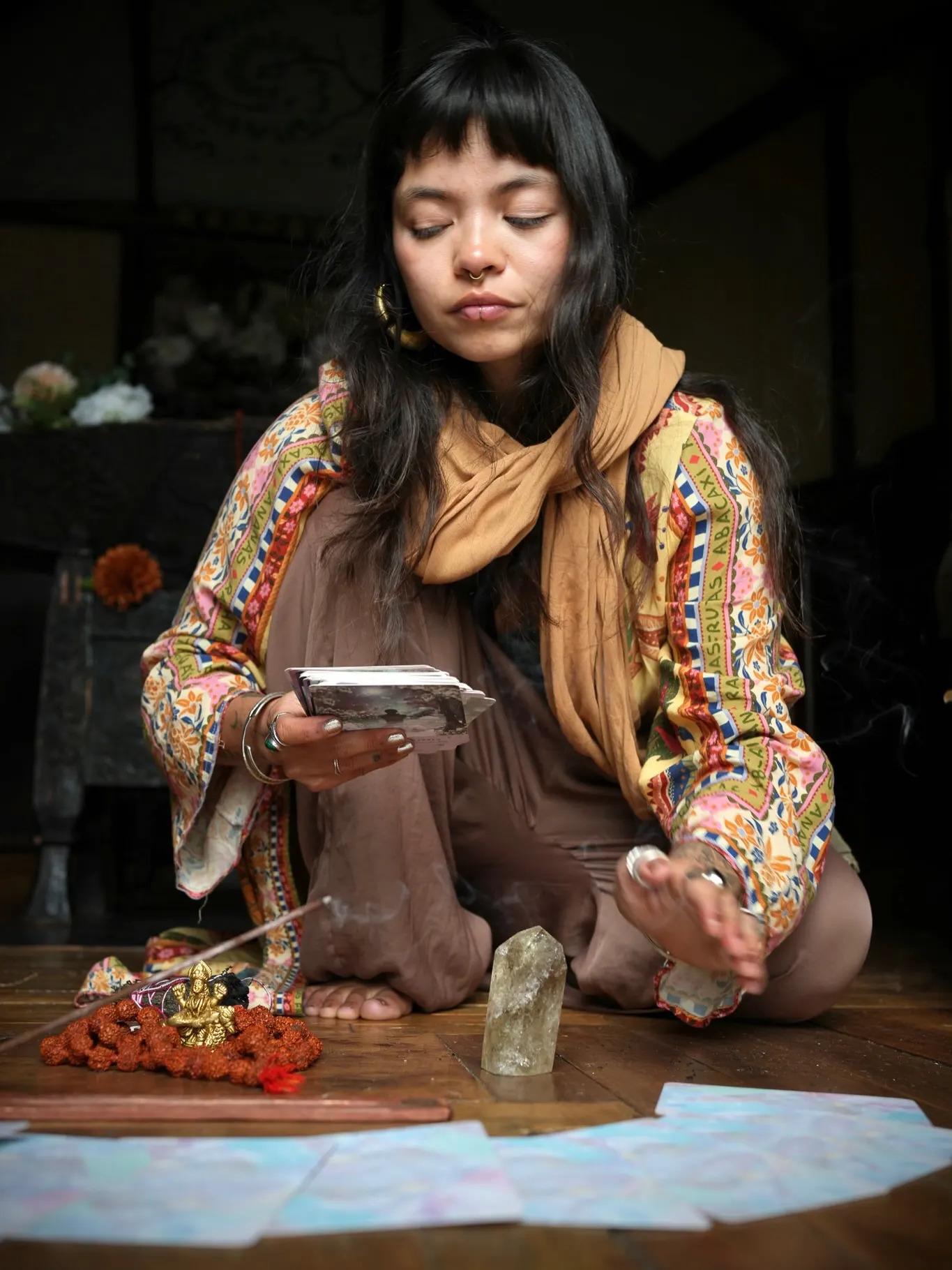 Dani kneeling with oracle cards beside a small altar of crystals and flowers