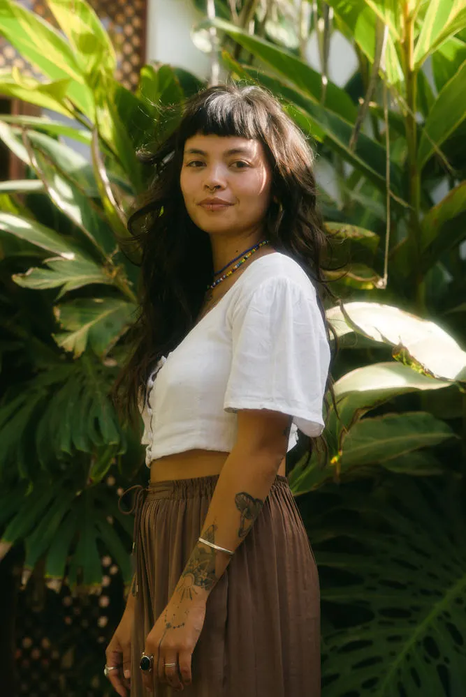 Dani smiling among large green leaves in a garden