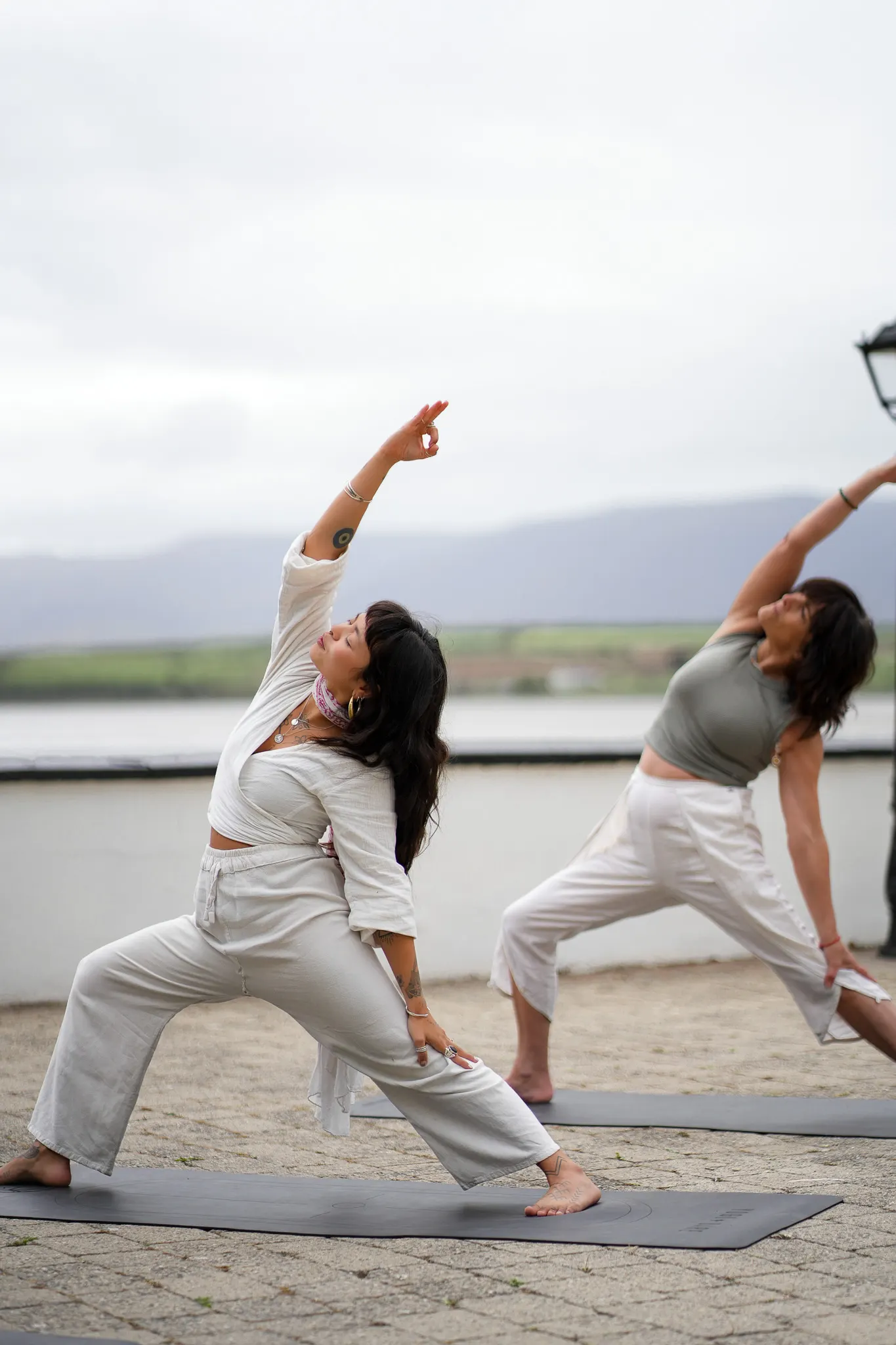 Catherine and Dani in side-angle pose on a terrace by the water