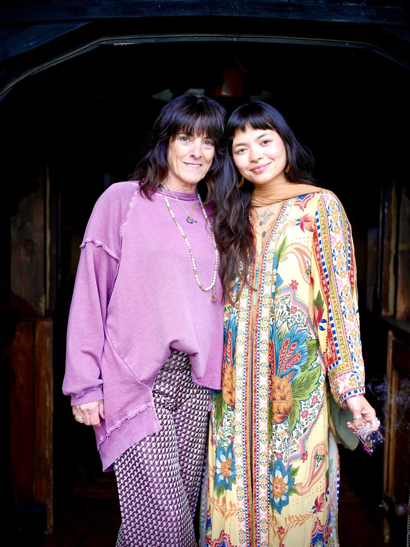 Catherine and Dani standing together, smiling, at a dark wooden doorway