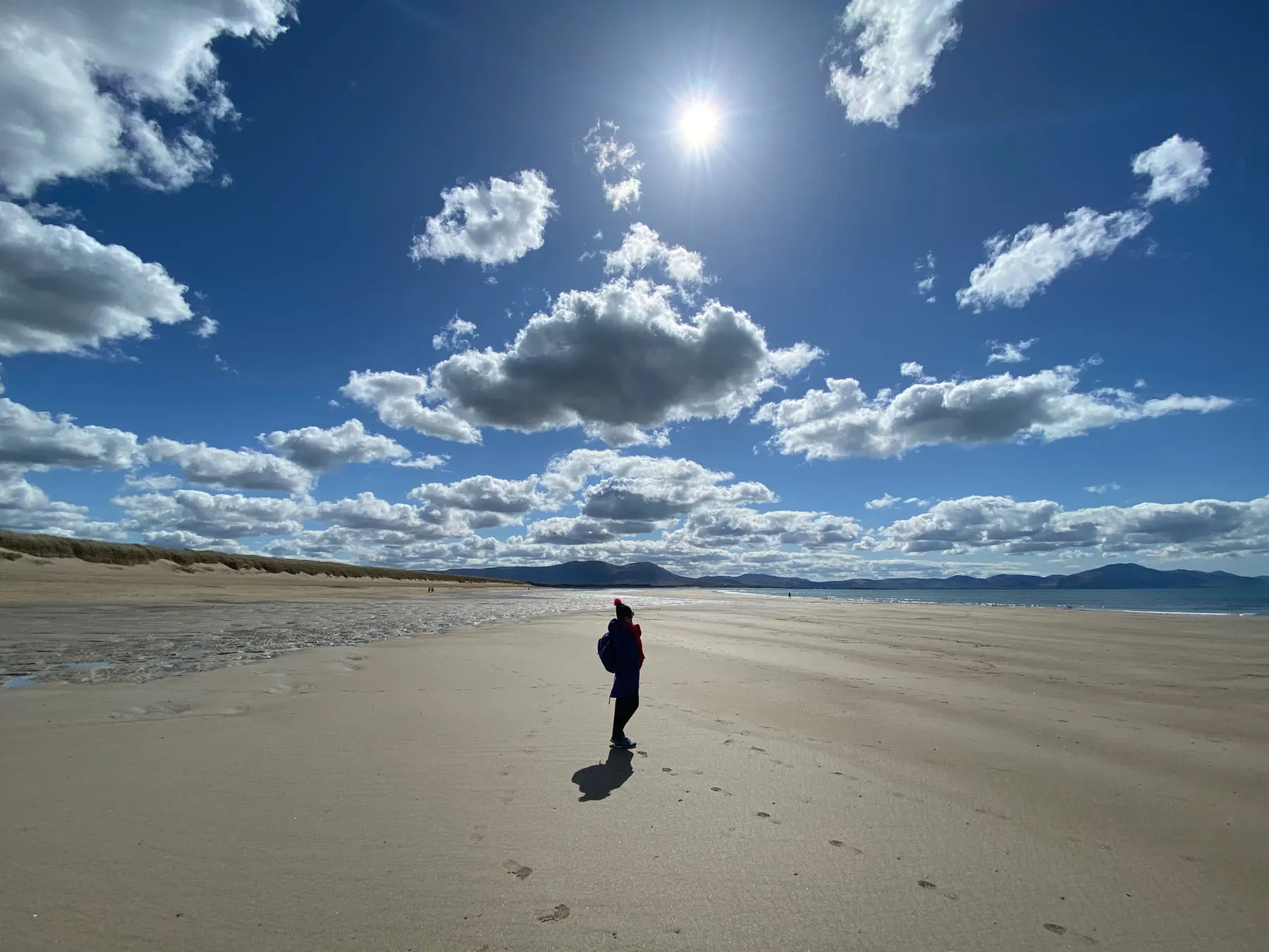 A lone walker on the wide sands of Barrow Beach under a bright sky
