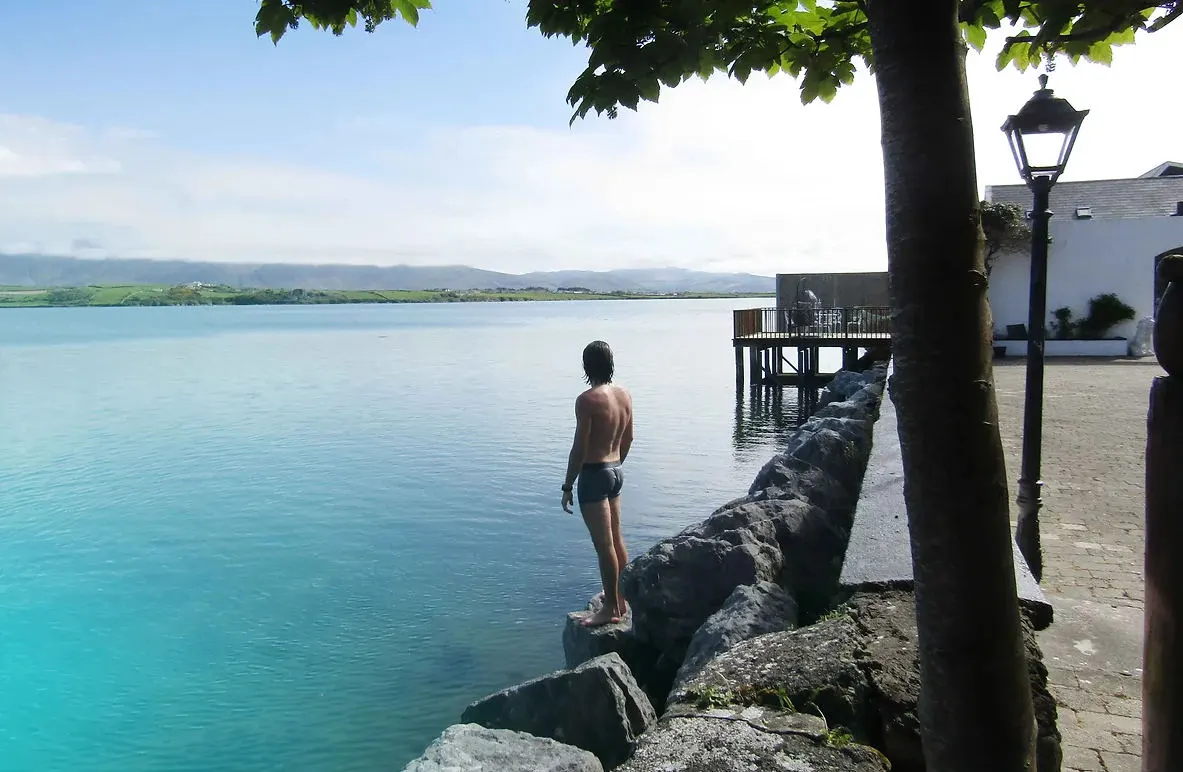 A swimmer about to dip into the clear harbour water from the rocks