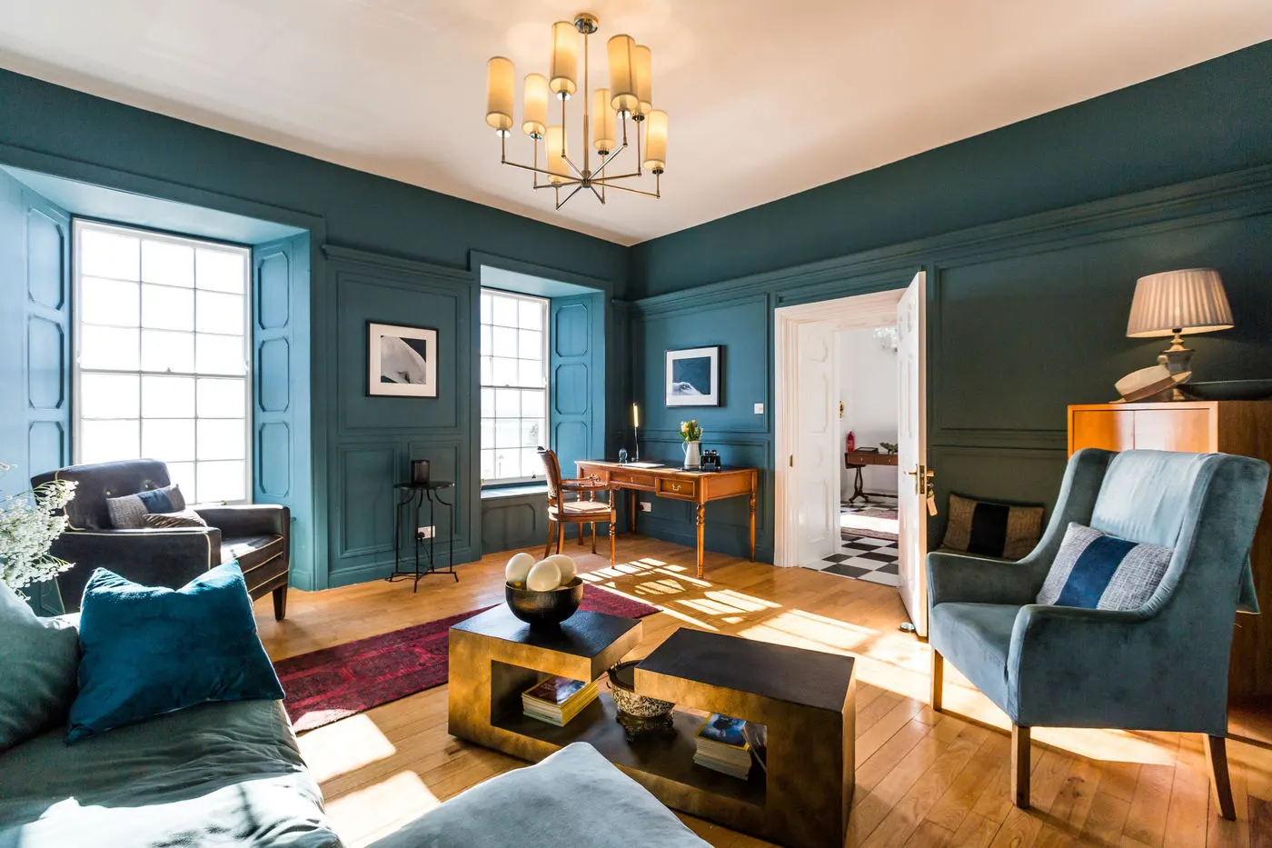The library at Barrow House with deep teal walls and an open fire