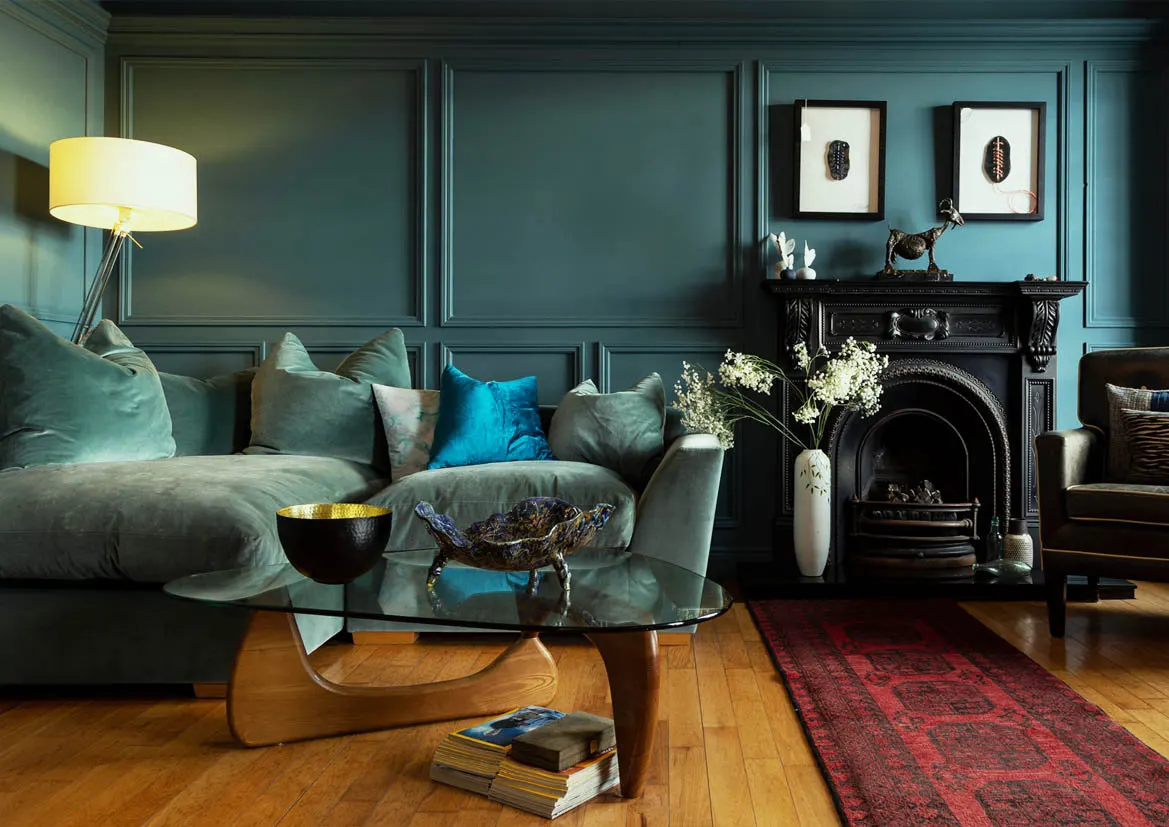 A teal sitting room with an open fireplace and deep sofas
