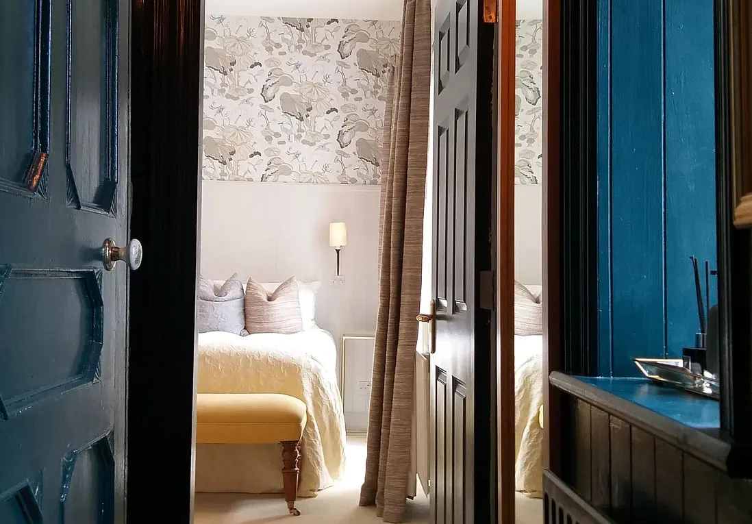 A guest bedroom glimpsed through deep teal doors