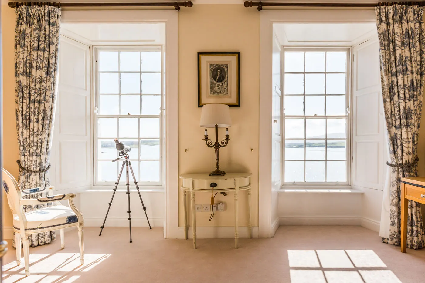 Tall sash windows looking out to the bay, with a telescope
