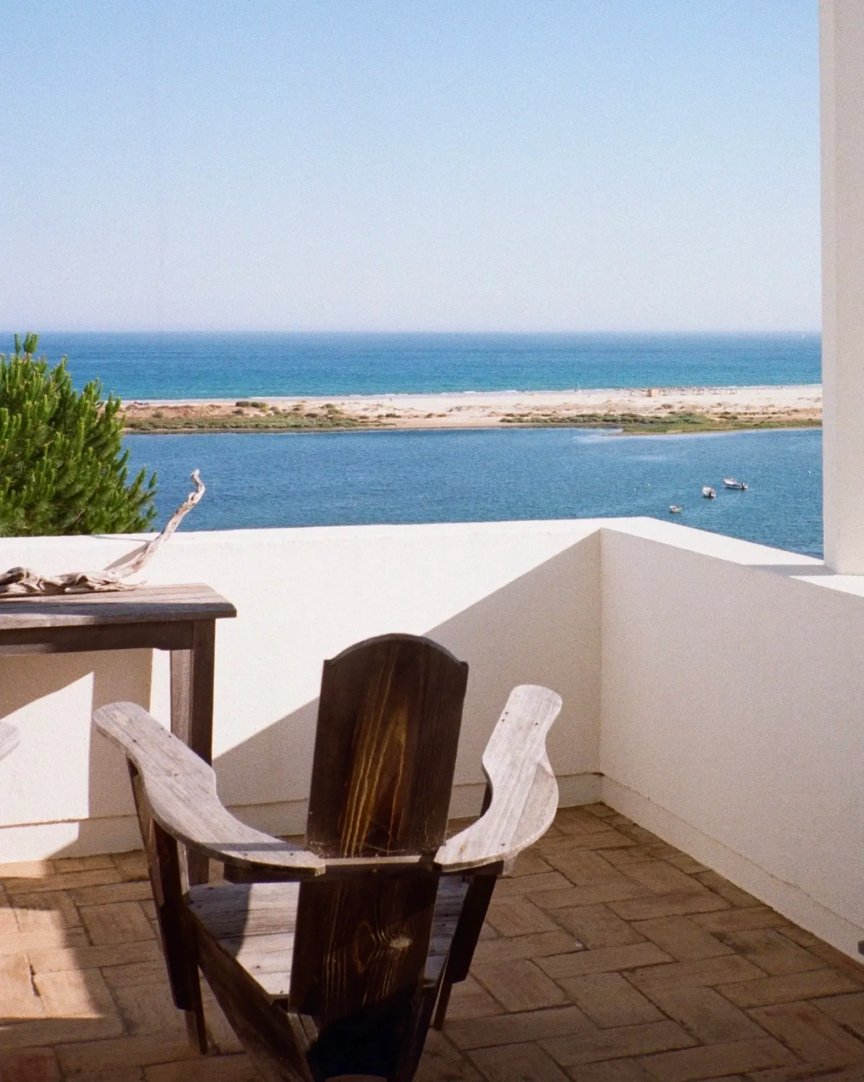 A wooden chair on a private balcony looking out over the lagoon and the sea