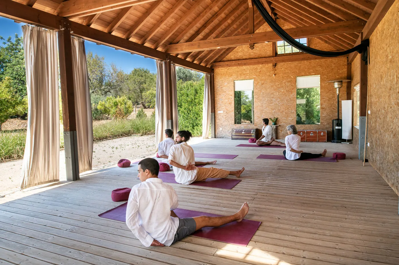 A group practising on mats in an open-sided yoga space
